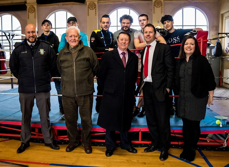 Sir Dave Richards with Jason Mace, John Jo Irwin and Jackie Irwin in front of a boxing ring