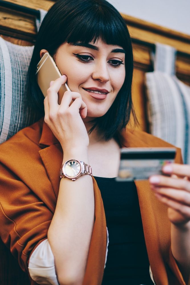 A young black haired lady makes a paymenht by telephone