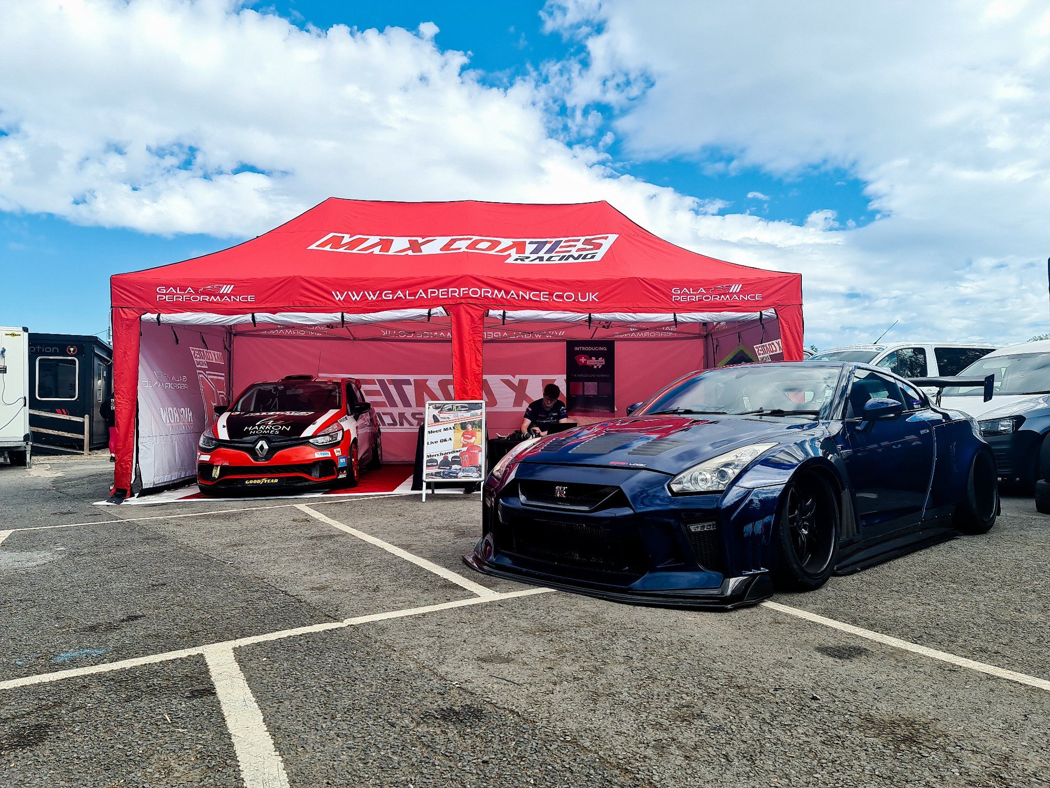 a printed red gazebo sits behind a sporty black racing car