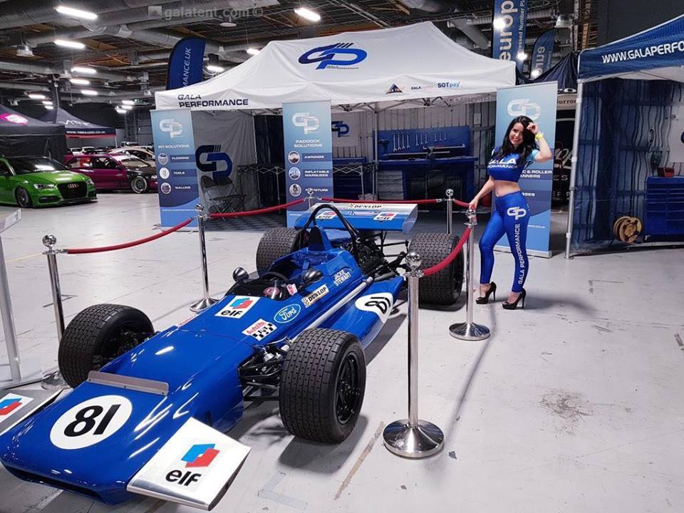 gazebo and race car at trade show, with model posing