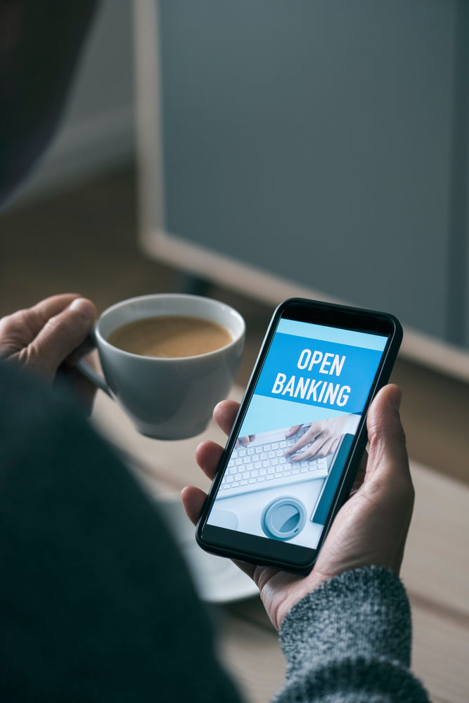 somebody looks at a smart phone with the words "open banking" displayed