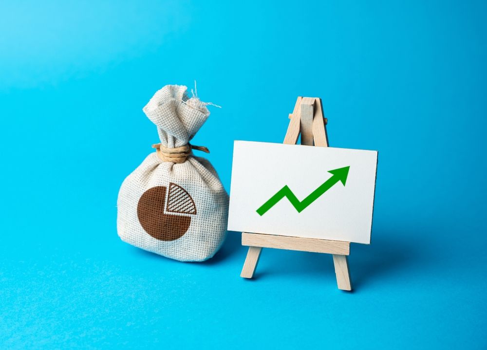 a bag of money with a board showing an upward trend
