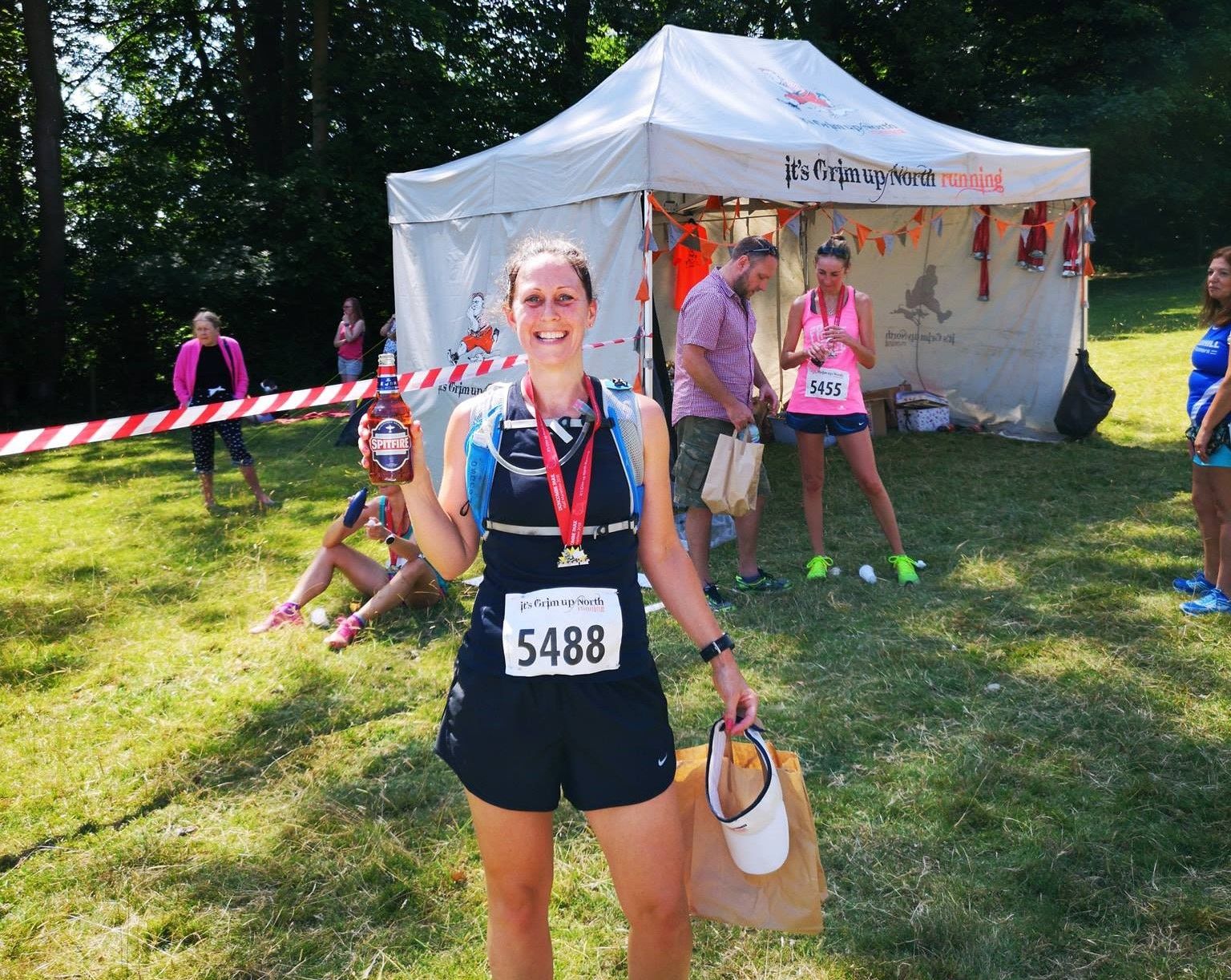 A happy runner shows off her medal in front of a gazbeo