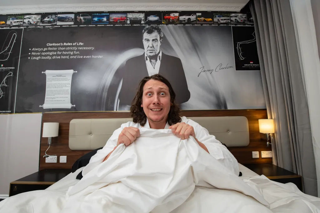 Journalist sits in bed in front of Jeremy Clarkson background